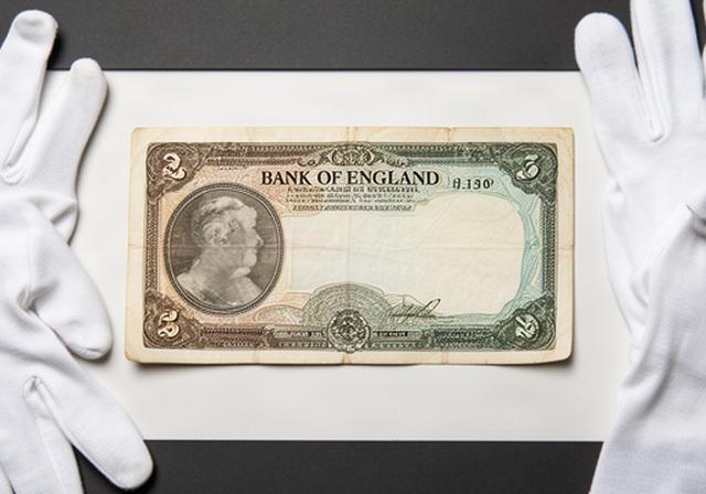 Historic Bank of England ten-pound note laid flat with archival cotton gloves