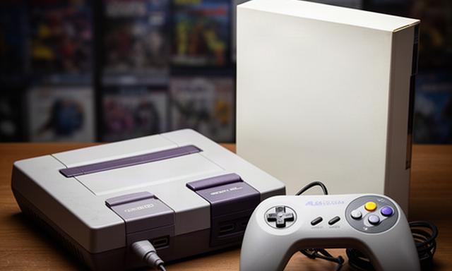 Retro 1990s games console with controller and boxed cartridge on a collector's table